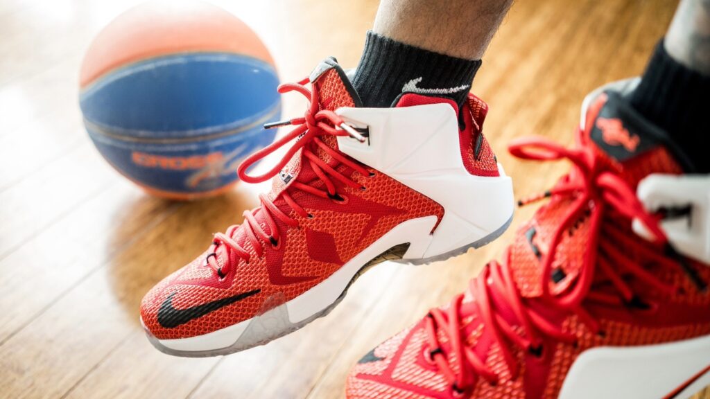 Close up of a pair of red shoes with a basketball in the background.